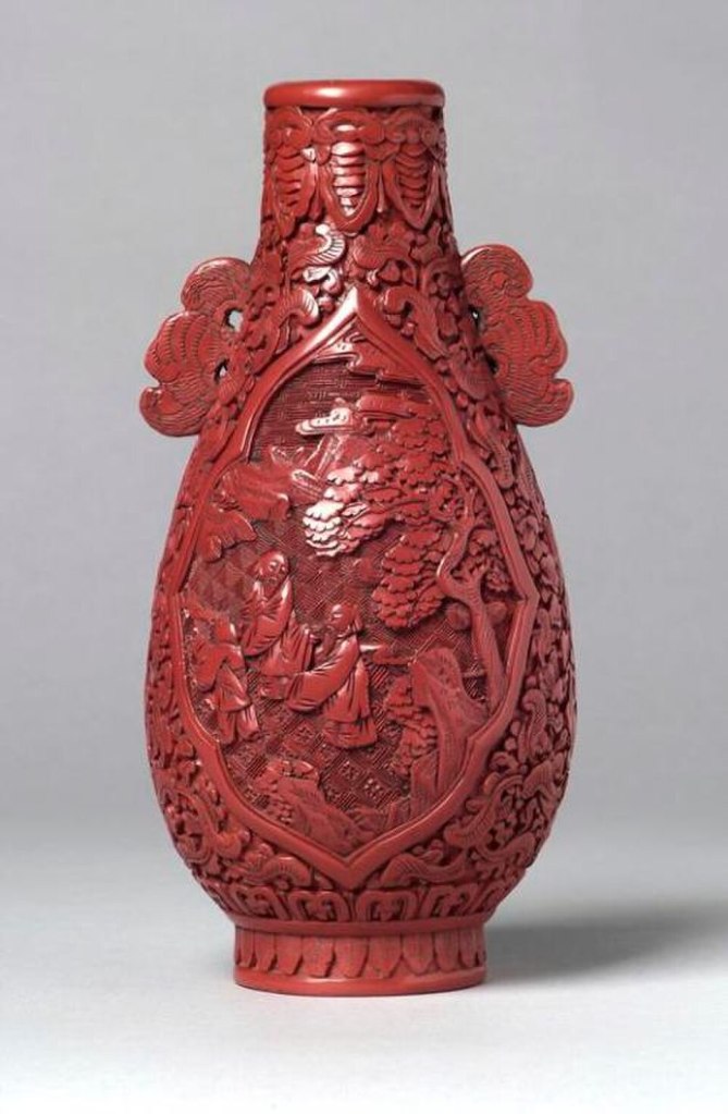 Chinese Cinnabar lacquer vase with intricate bat handle carvings.